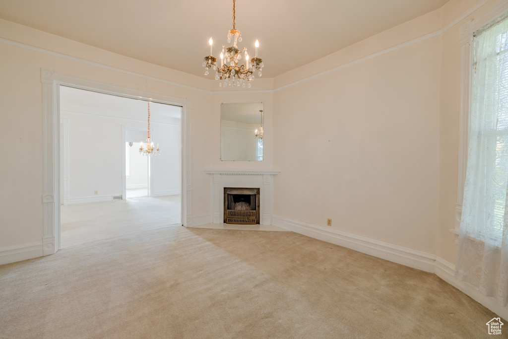 Unfurnished living room featuring light colored carpet and a chandelier