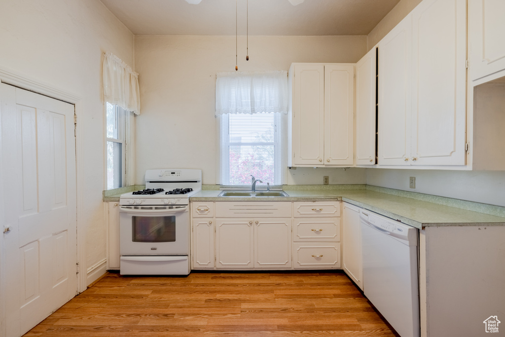 Kitchen featuring white cabinetry, white appliances, and sink