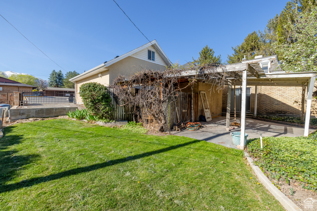 Rear view of property featuring a yard, a pergola, and a patio