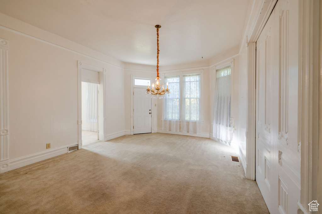 Carpeted spare room with an inviting chandelier