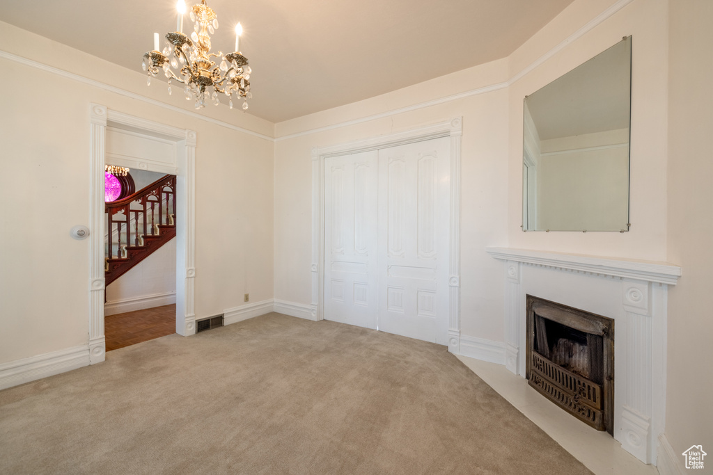 Unfurnished living room with carpet flooring and an inviting chandelier