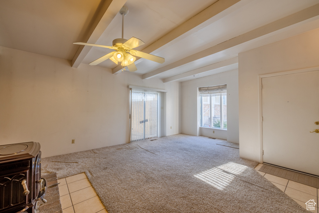 Unfurnished living room featuring ceiling fan, light colored carpet, and beam ceiling