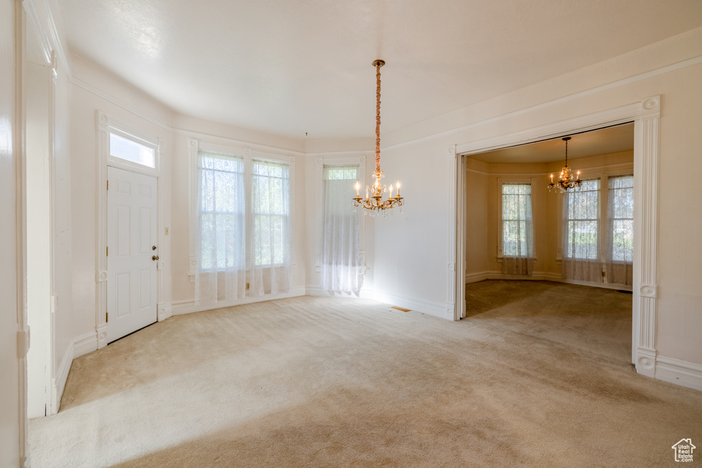 Interior space with light colored carpet and an inviting chandelier