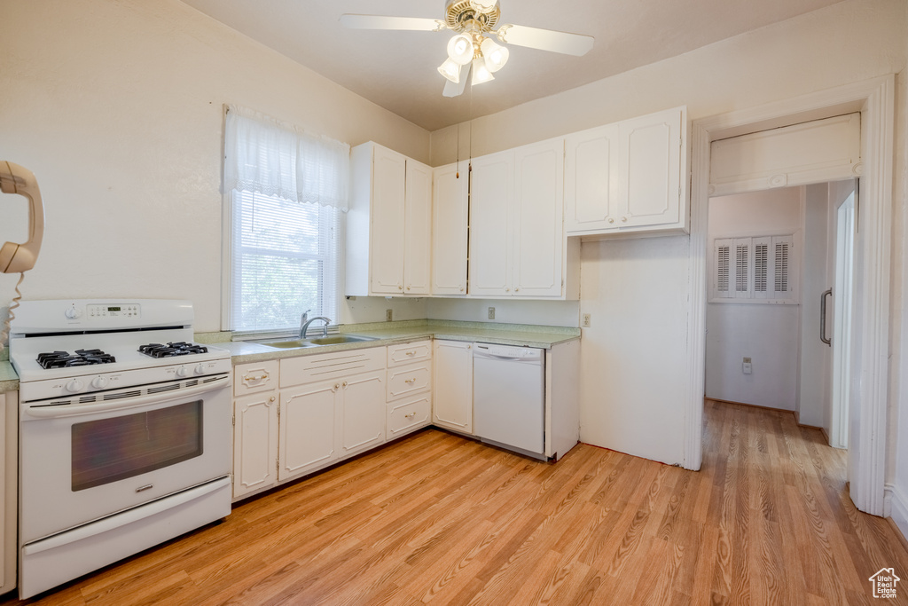 Kitchen with sink, light wood-type flooring, ceiling fan, white appliances, and white cabinets