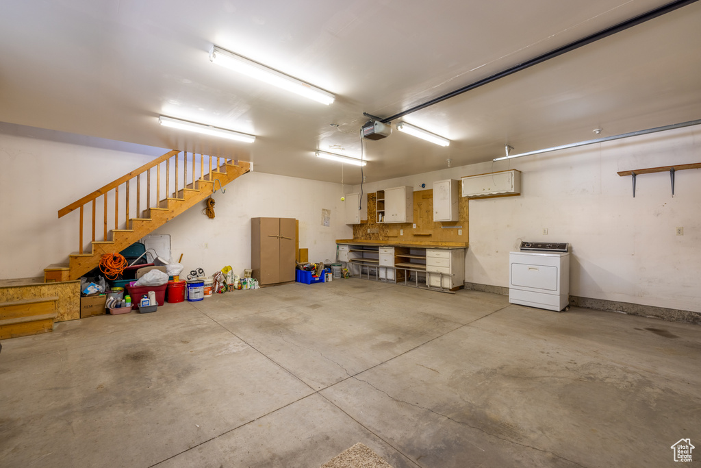 Garage with washer / clothes dryer, a garage door opener, and a workshop area