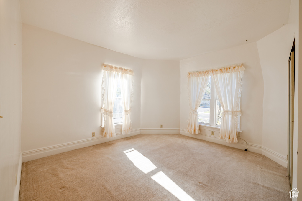 Empty room featuring light colored carpet and a healthy amount of sunlight