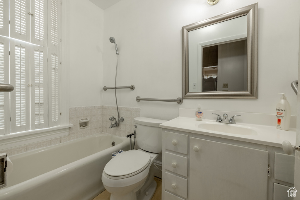 Bathroom featuring vanity, toilet, a washtub, and a wealth of natural light