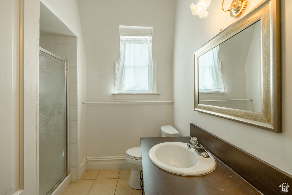 Bathroom with an enclosed shower, sink, tile patterned floors, and toilet