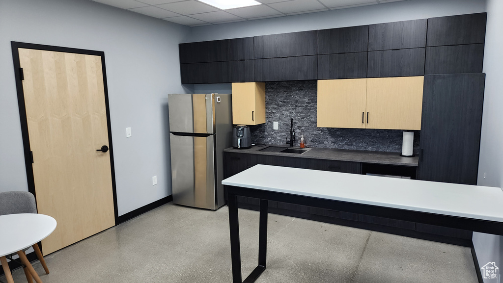 Kitchen with sink, a drop ceiling, backsplash, and stainless steel refrigerator
