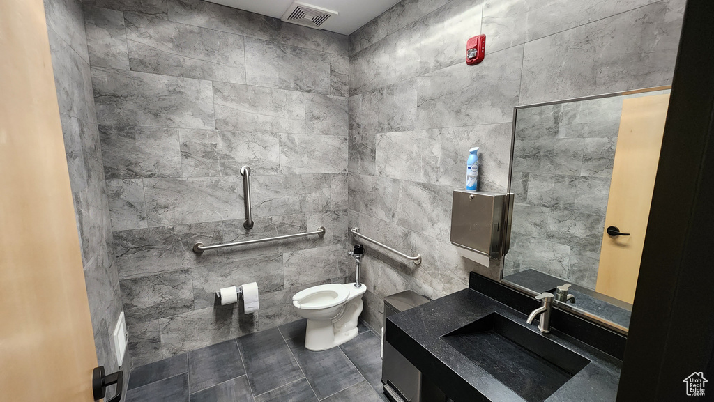 Bathroom with vanity, tile walls, tile patterned floors, and toilet
