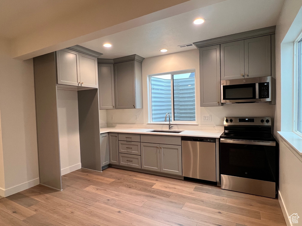 Kitchen featuring stainless steel appliances, light hardwood / wood-style floors, sink, and gray cabinetry
