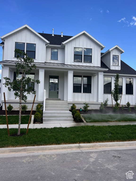 Modern farmhouse with a porch, a standing seam roof, board and batten siding, and metal roof