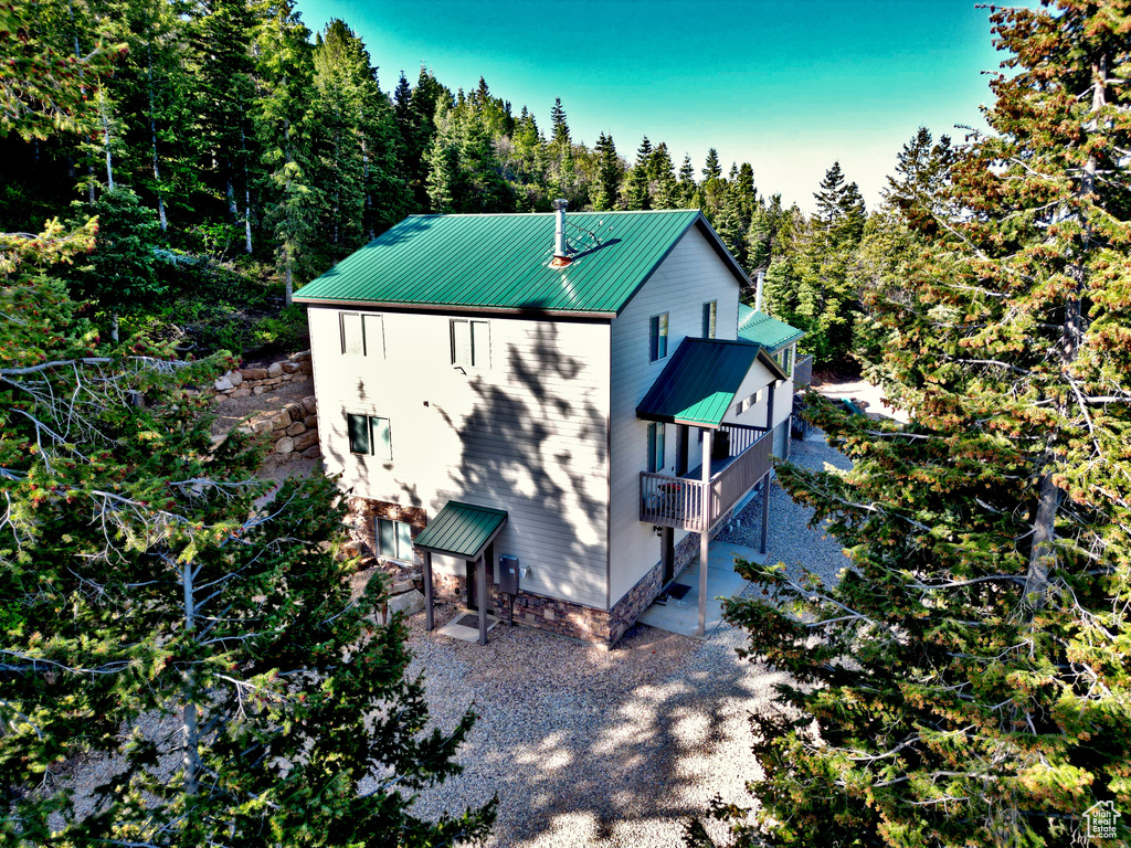 View of side of property with metal roof and a view of trees