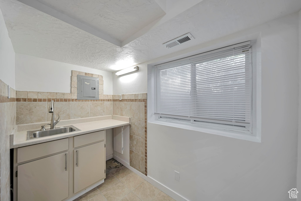 Bathroom with tile walls, vanity, electric panel, tile patterned floors, and a textured ceiling