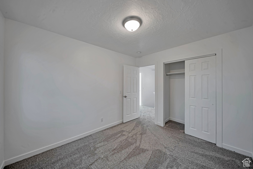 Unfurnished bedroom with carpet floors, a textured ceiling, and a closet
