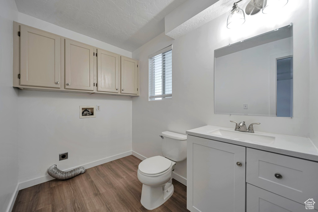 Bathroom featuring vanity, hardwood / wood-style floors, a textured ceiling, and toilet