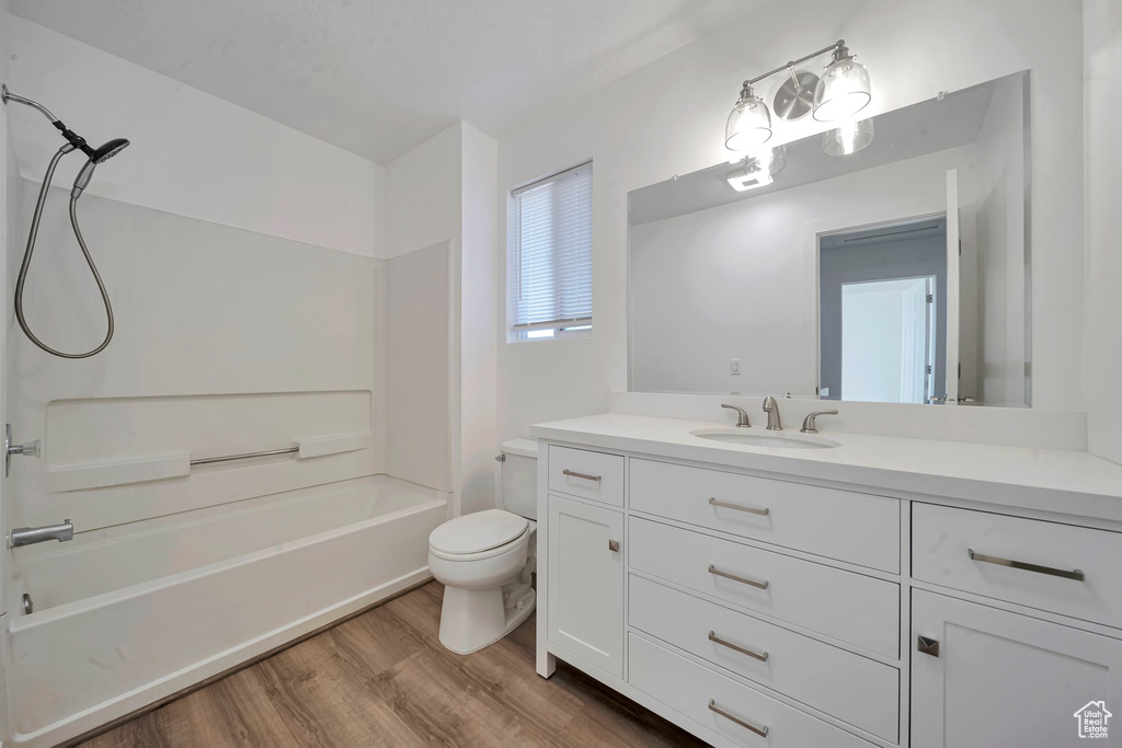 Full bathroom with hardwood / wood-style flooring, vanity, toilet, and shower / bath combination