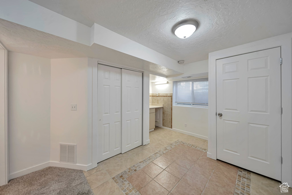 Interior space with connected bathroom, a textured ceiling, and light tile patterned floors