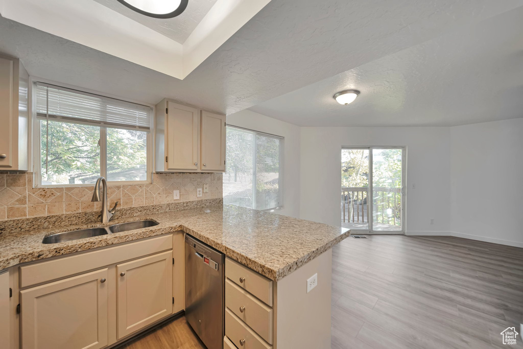 Kitchen featuring dishwasher, sink, kitchen peninsula, and backsplash