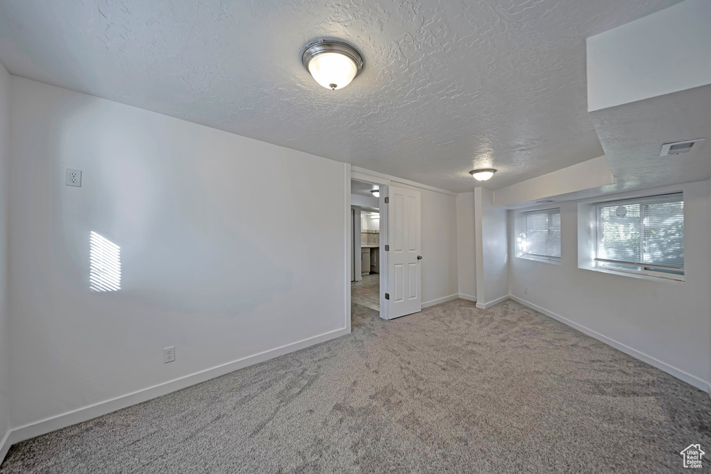 Carpeted spare room featuring a textured ceiling