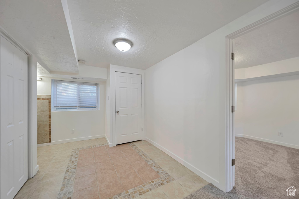 Corridor with light tile patterned floors and a textured ceiling