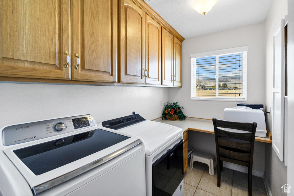 Washroom featuring cabinets, washer and clothes dryer, and light tile patterned floors