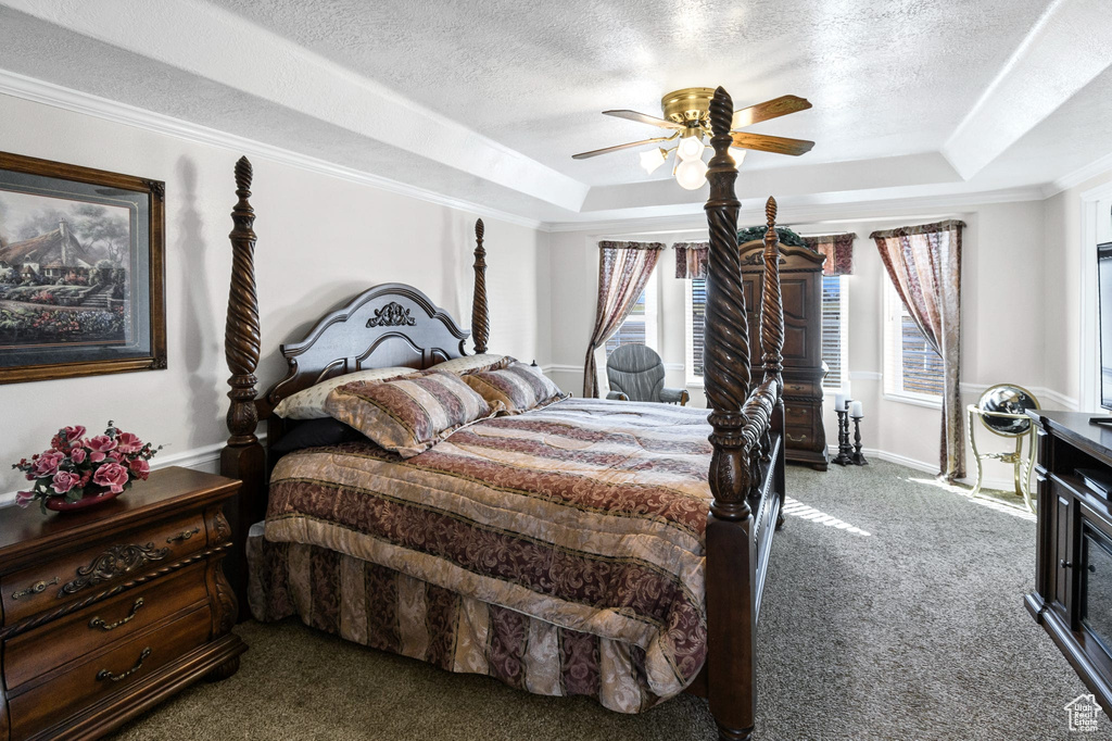 Carpeted bedroom with crown molding, ceiling fan, a raised ceiling, and a textured ceiling
