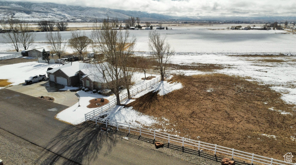 Snowy aerial view featuring a mountain view and a rural view