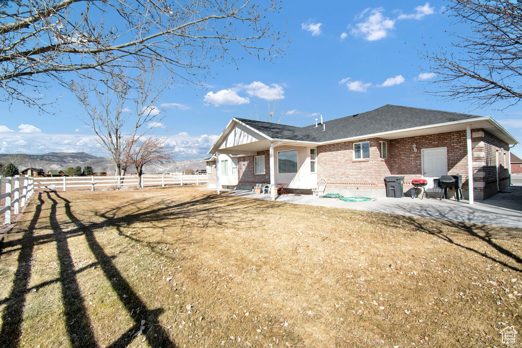 Rear view of property with a mountain view, a yard, and a patio area