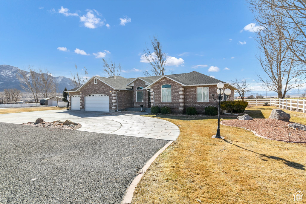 Ranch-style home featuring a garage, a mountain view, and a front lawn