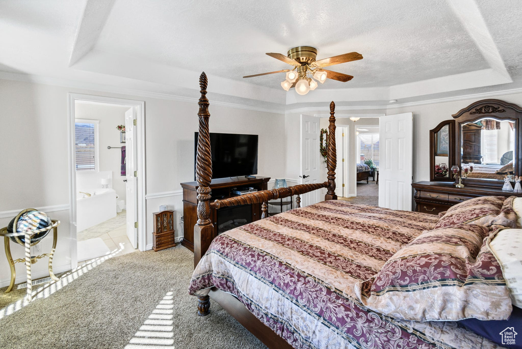 Bedroom with ceiling fan, a tray ceiling, light colored carpet, and a textured ceiling
