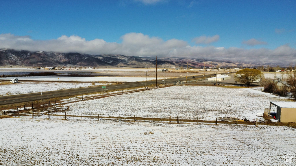 Yard covered in snow featuring a mountain view and a rural view