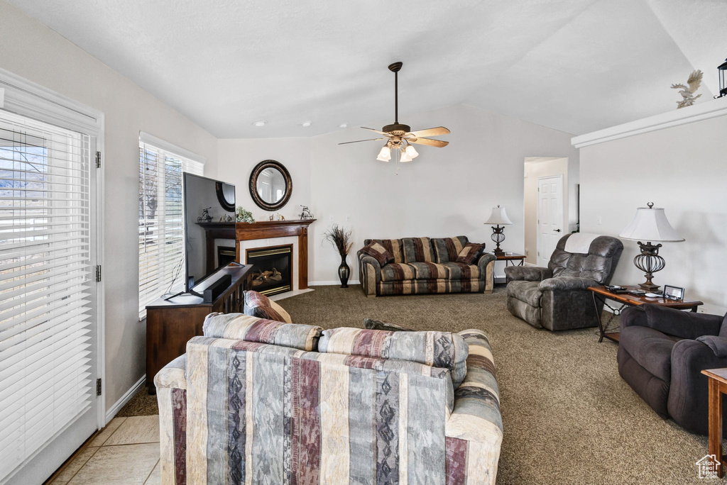 Carpeted living room with ceiling fan and lofted ceiling