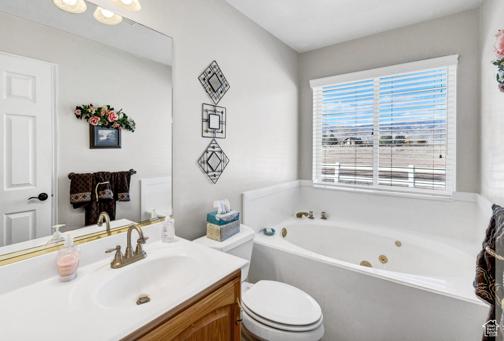 Bathroom featuring vanity, a bath, and toilet