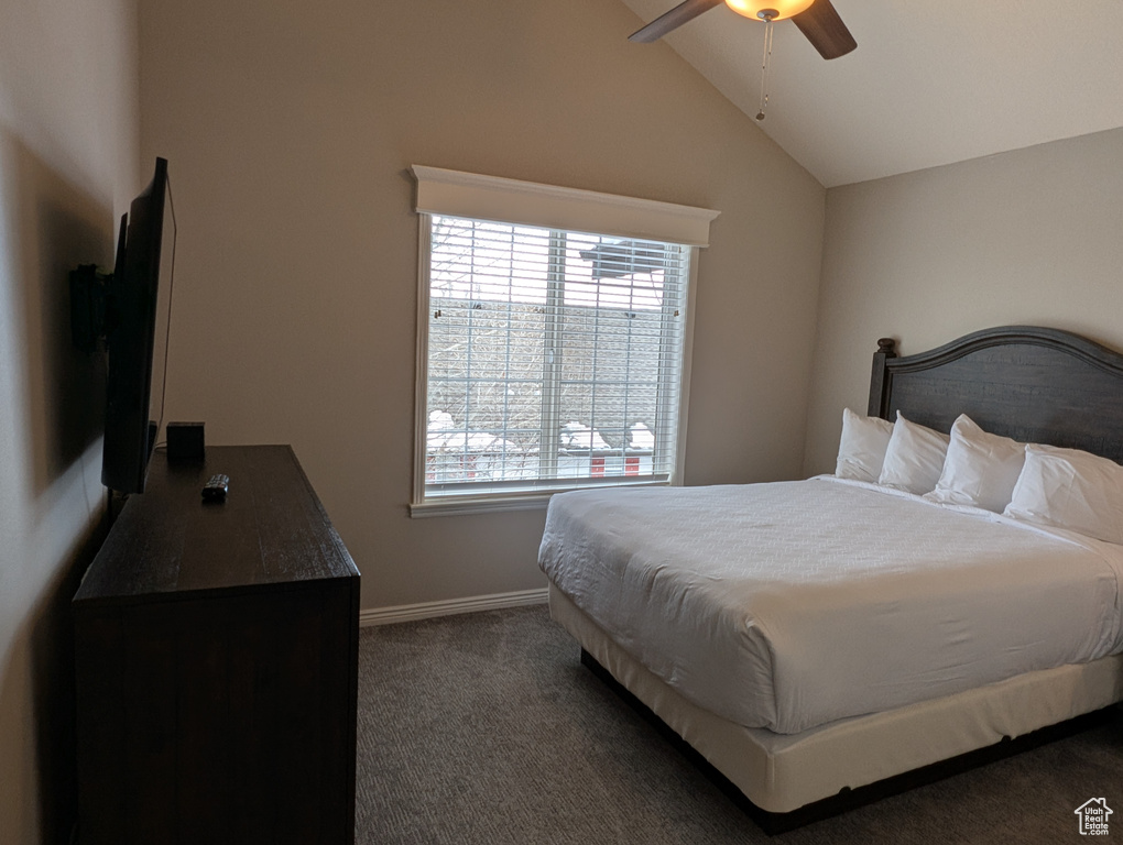 Carpeted bedroom featuring ceiling fan and vaulted ceiling