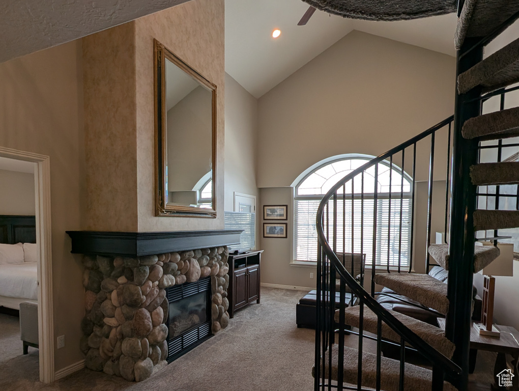 Bedroom featuring light carpet, a fireplace, high vaulted ceiling, and a water view