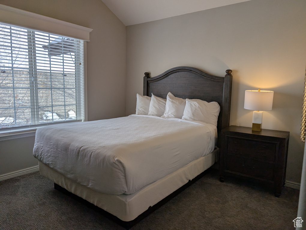 Bedroom with lofted ceiling and dark carpet