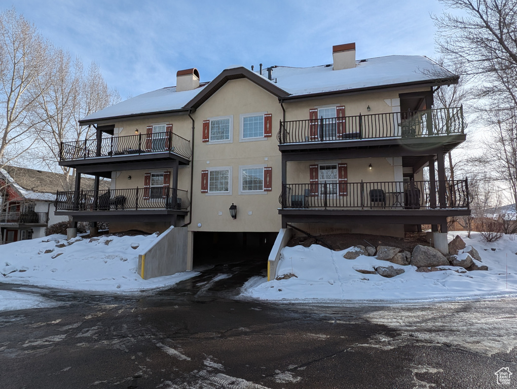 Snow covered rear of property featuring a balcony