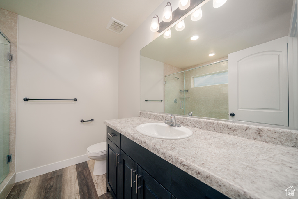 Bathroom featuring hardwood / wood-style flooring, vanity, toilet, and walk in shower