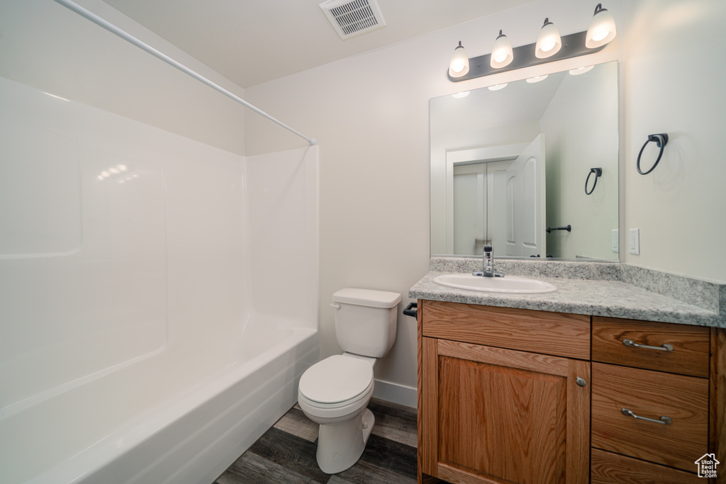 Full bathroom with vanity, wood-type flooring, washtub / shower combination, and toilet