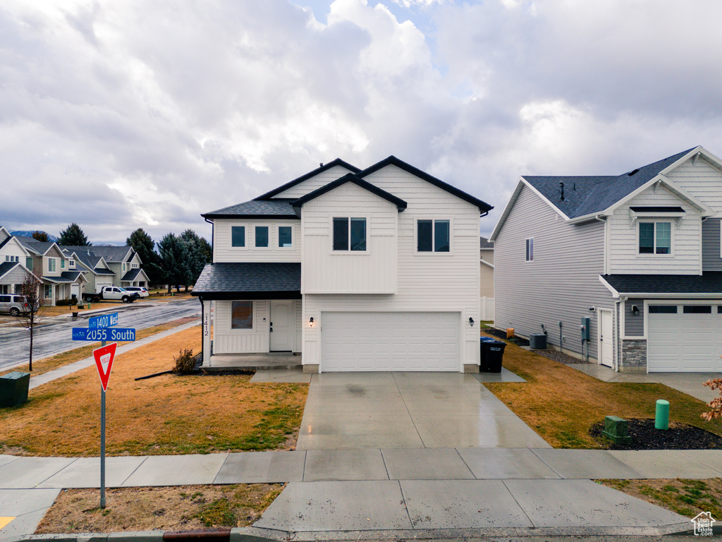 Front facade with a garage, a front yard, and central air condition unit