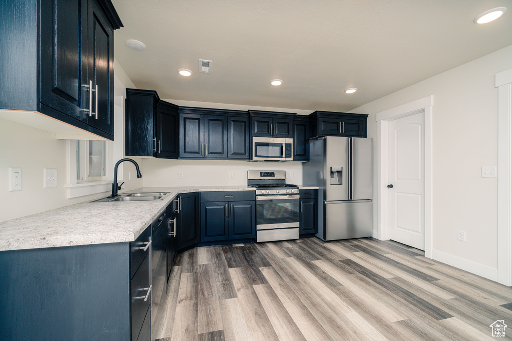 Kitchen featuring appliances with stainless steel finishes, sink, and light wood-type flooring