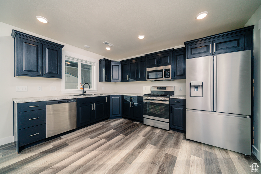 Kitchen with stainless steel appliances, hardwood / wood-style flooring, and sink