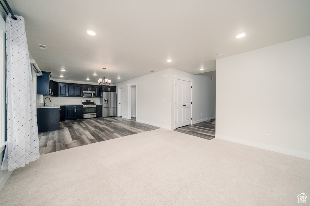 Living room featuring an inviting chandelier, sink, and dark carpet