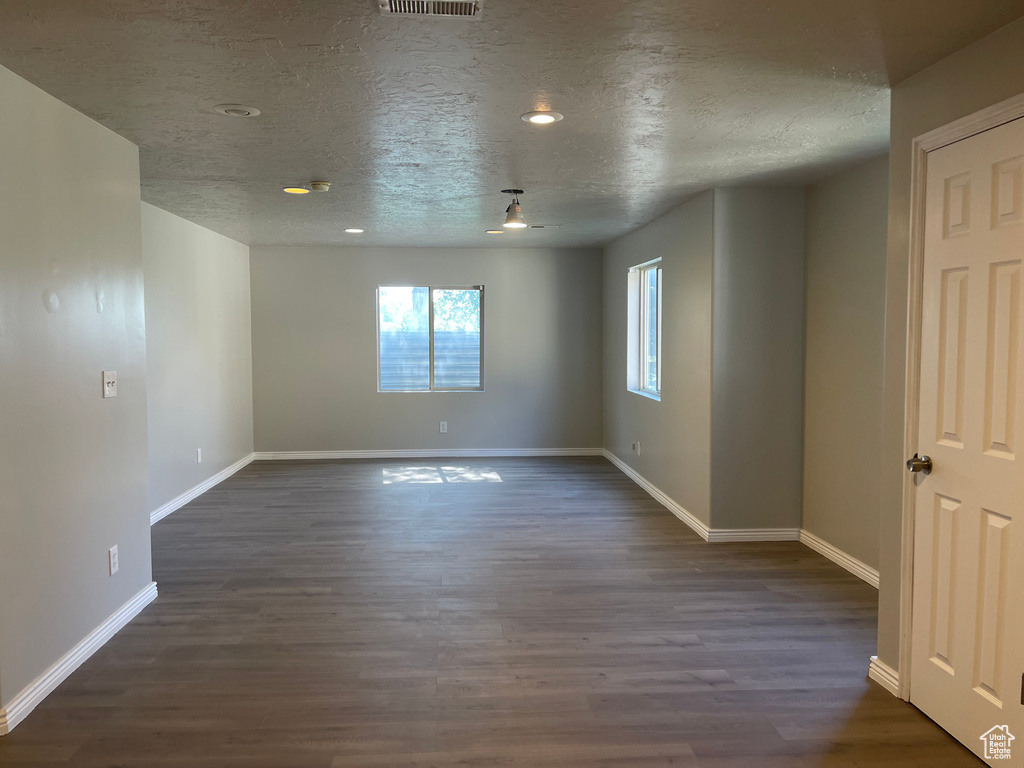 Unfurnished room featuring dark hardwood / wood-style flooring and a textured ceiling
