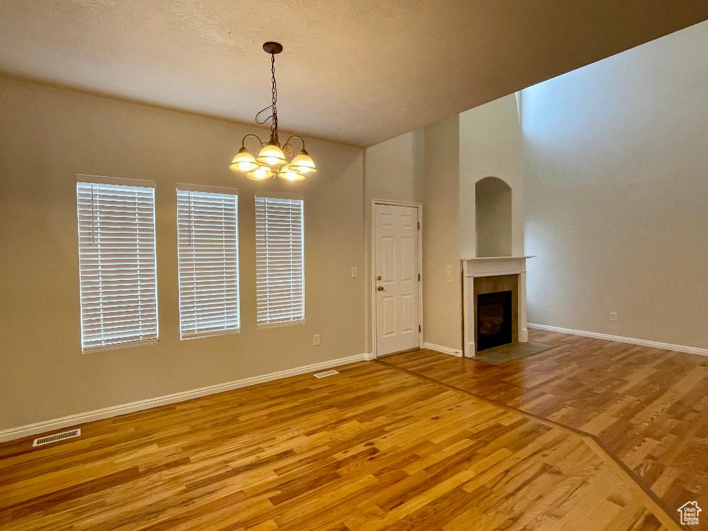 Unfurnished living room featuring wood-type flooring and an inviting chandelier