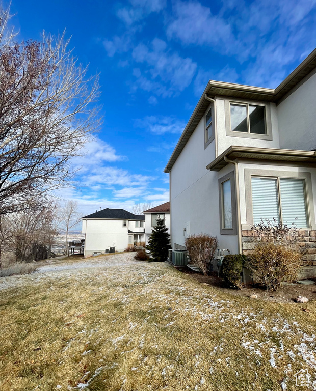 View of side of property featuring central AC unit and a yard