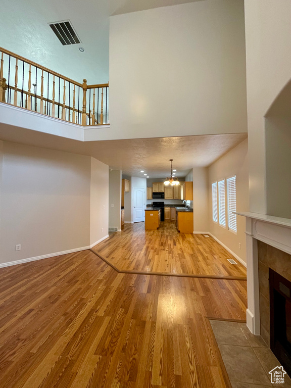 Unfurnished living room featuring a high ceiling, a tile fireplace, and light hardwood / wood-style flooring
