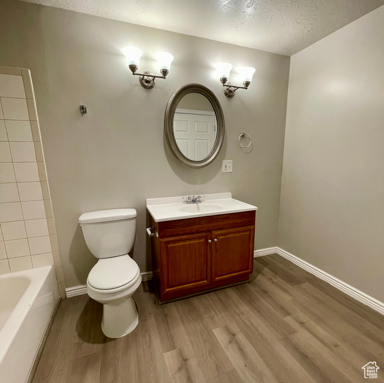 Bathroom featuring hardwood / wood-style flooring, vanity, toilet, and a textured ceiling