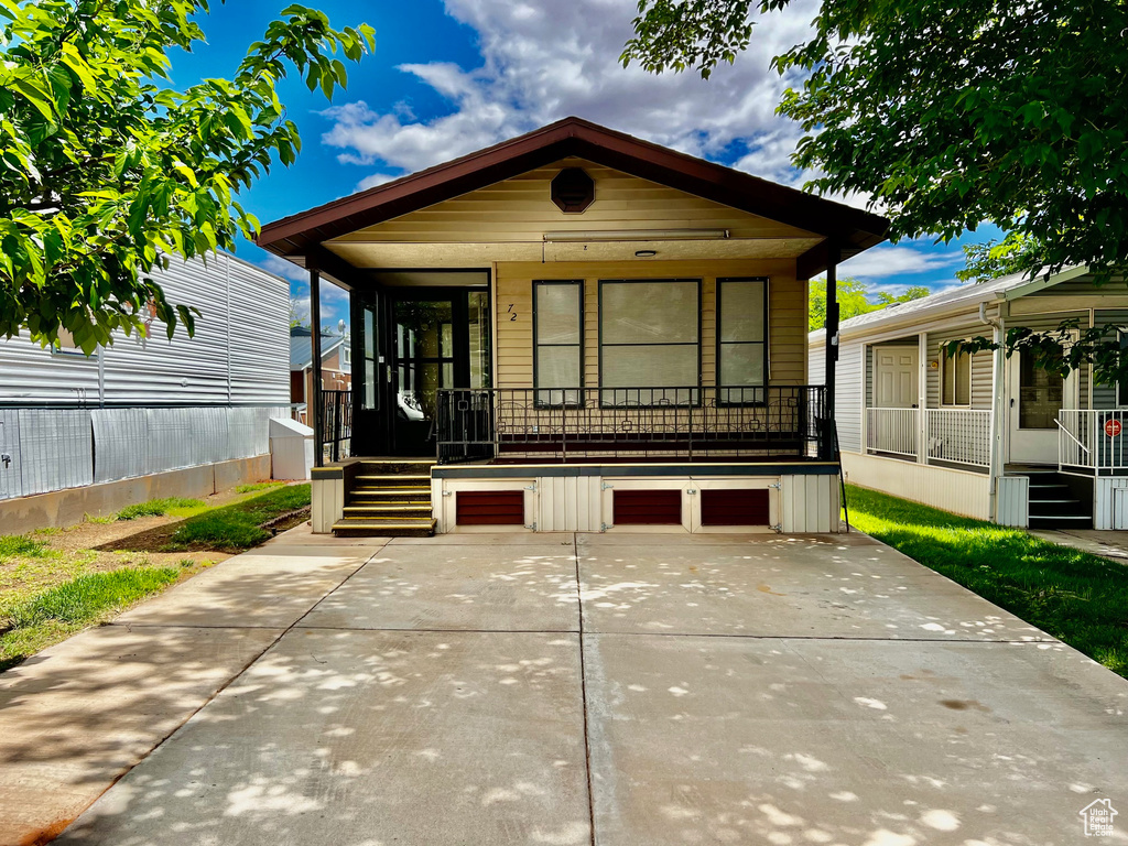 Shotgun-style home featuring covered porch, stairway, driveway, and a garage